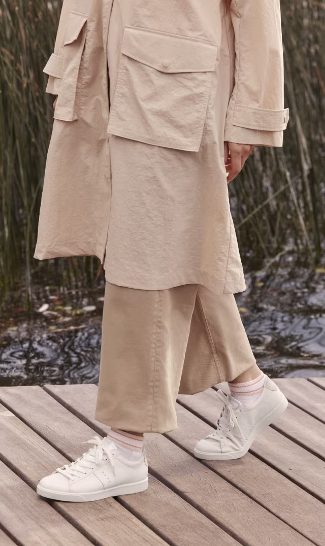 ECCO Street Lite women's white leather sneakers with minimalist design and classic laces on a wooden boardwalk.