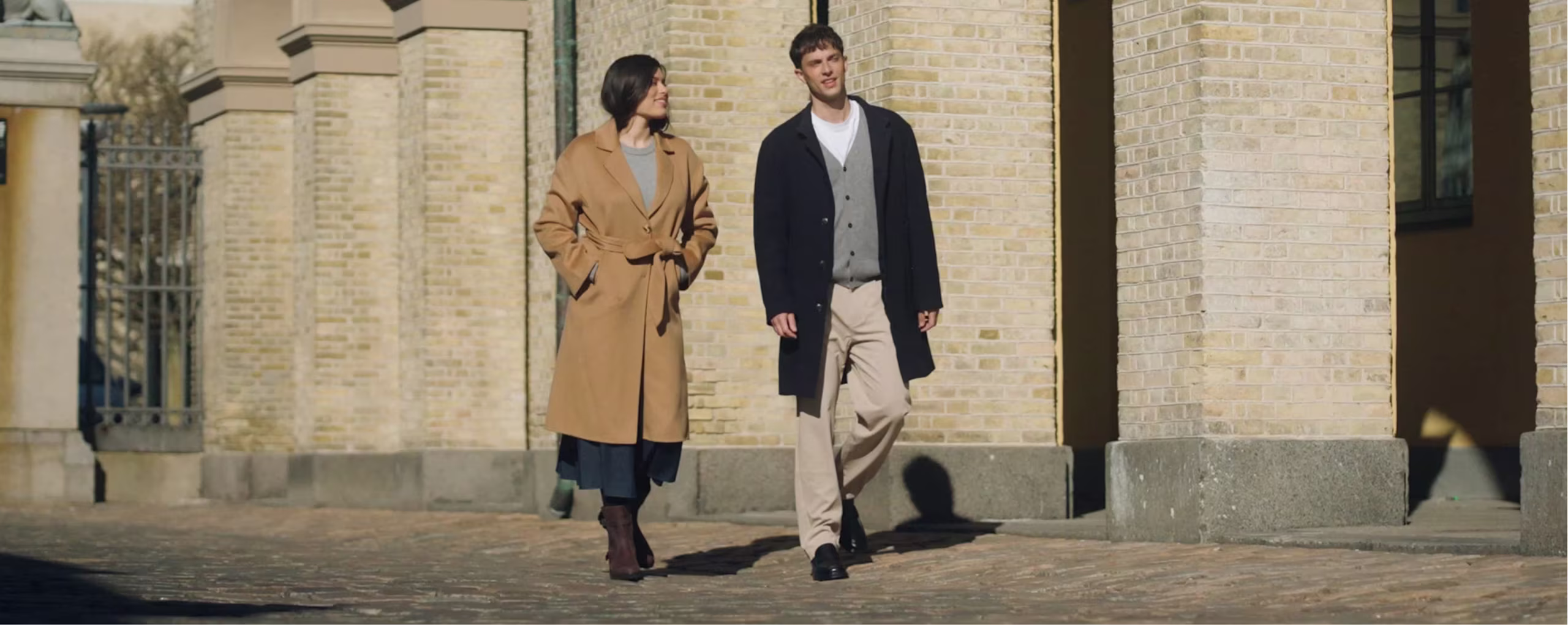 Man and woman walking outdoors in tailored coats with ECCO black leather dress boots and shoes
