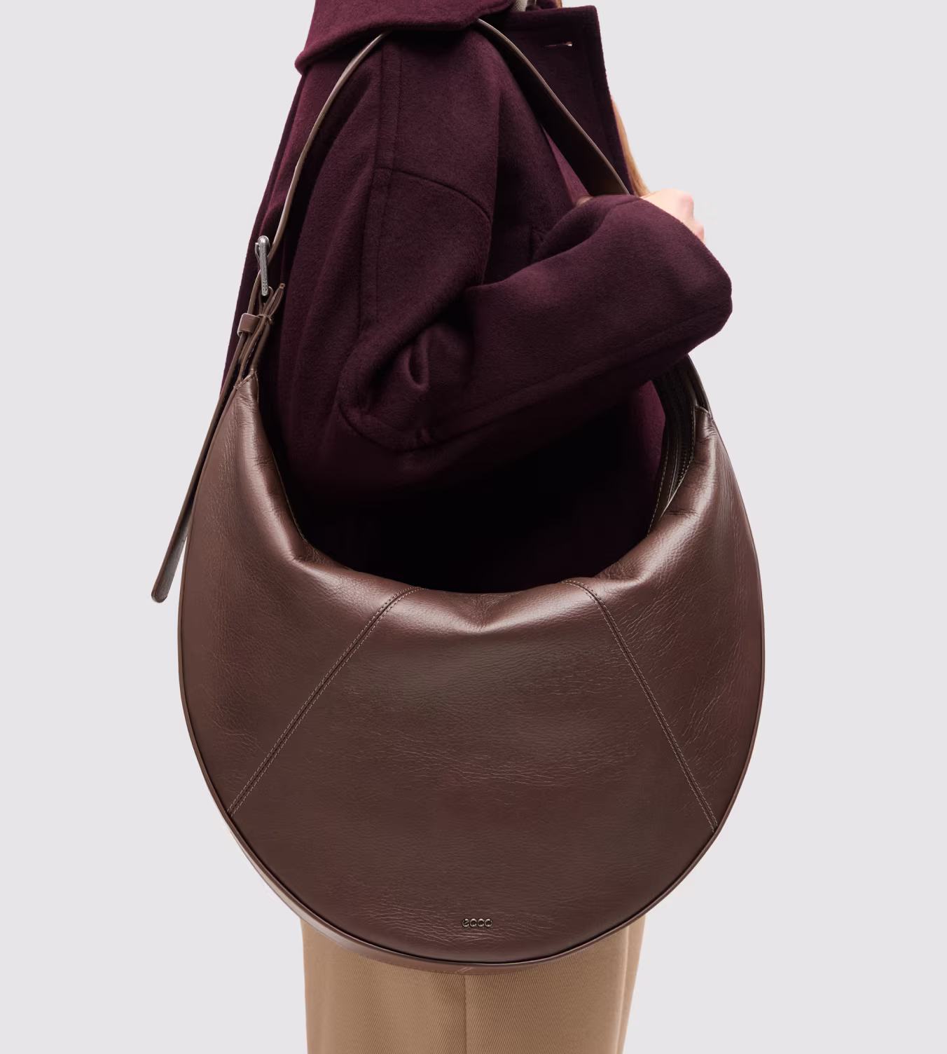 Sculpted from rich brown leather into a striking crescent silhouette, this slouchy hobo bag embodies Scandinavian luxury and spacious functionality.