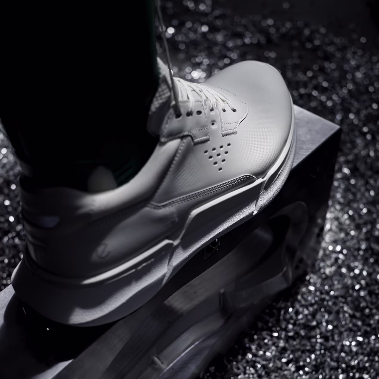 Detailed macro shot focusing on the heel and sole connection of a white ECCO shoe during the FLUIDFORM direct injection manufacturing process.
