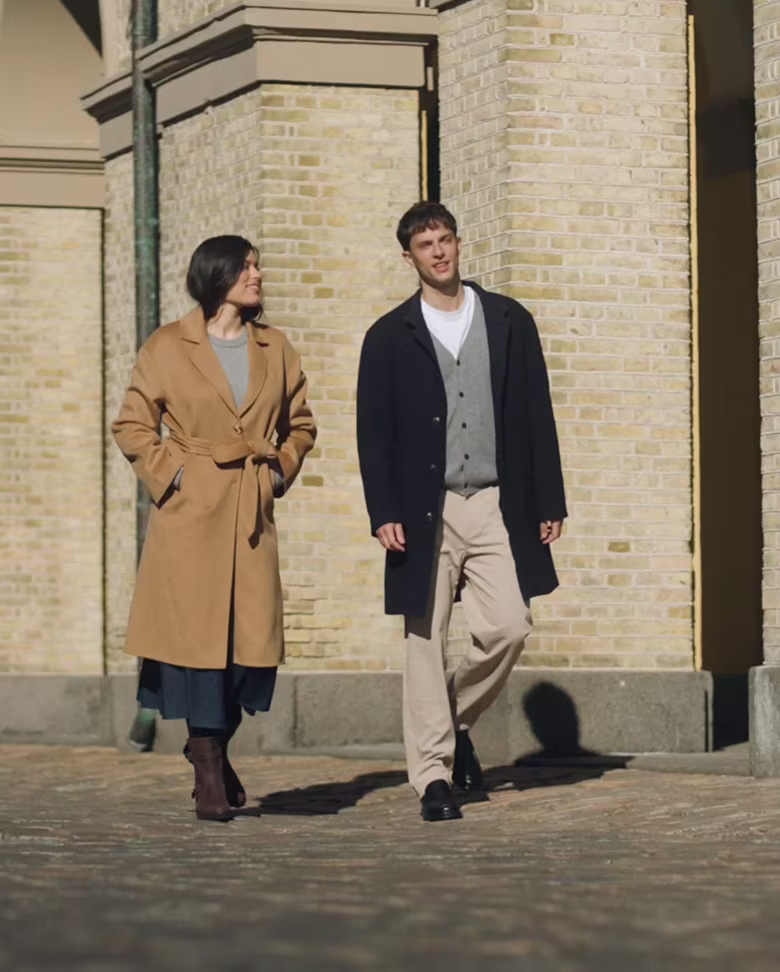 Man and woman walking outdoors in tailored coats with ECCO black leather dress shoes and boots