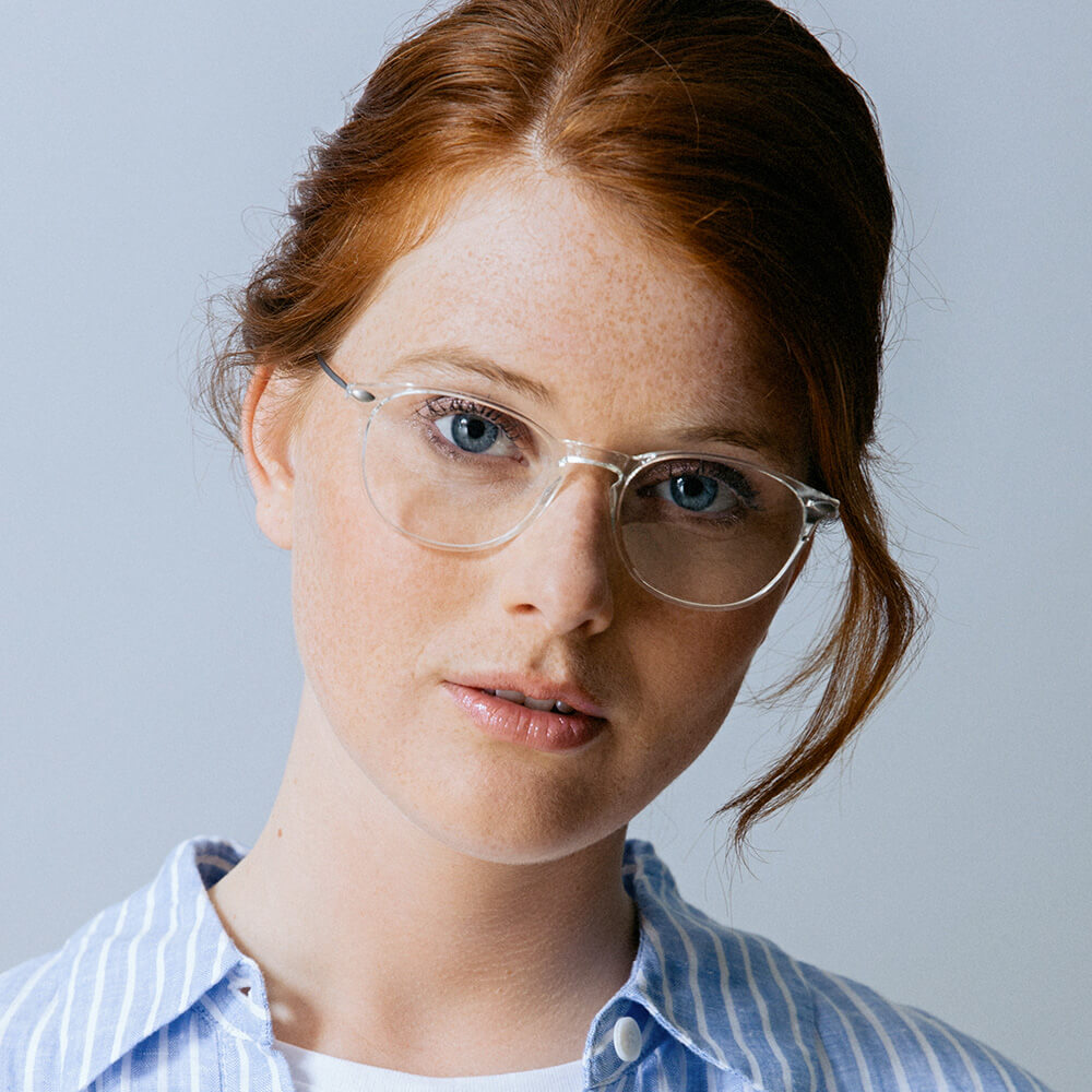 Essential reading glasses worn by a red-haired woman in blue shirt