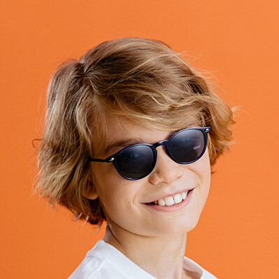 Paire de lunettes de soleil enfant portée par un garçon souriant 