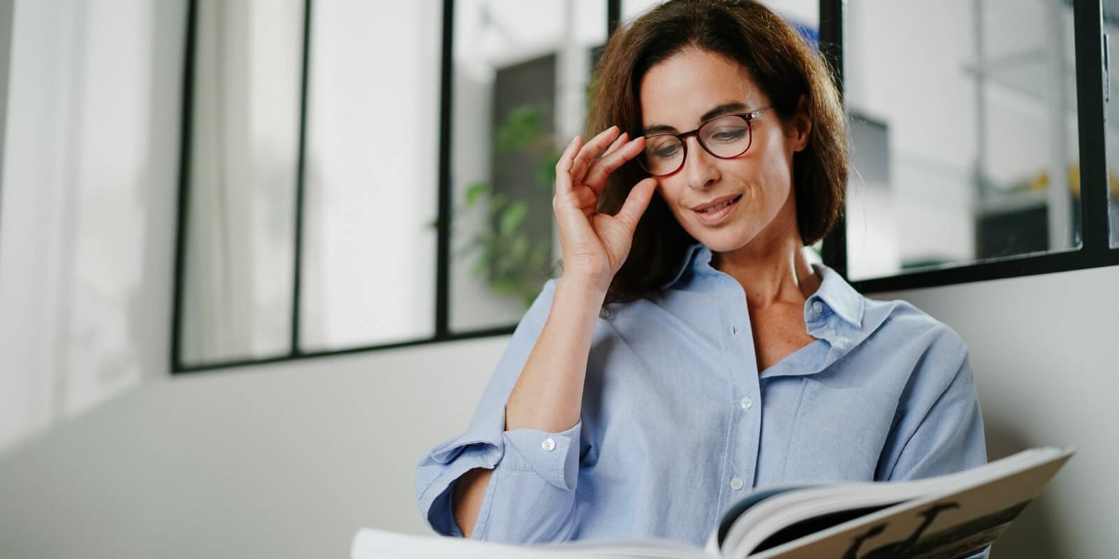 Pair of Nooz Optics reading glasses driven by a woman reading