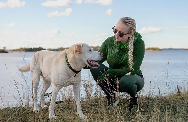 Nainen on kyykistyneenä koiran viereen.