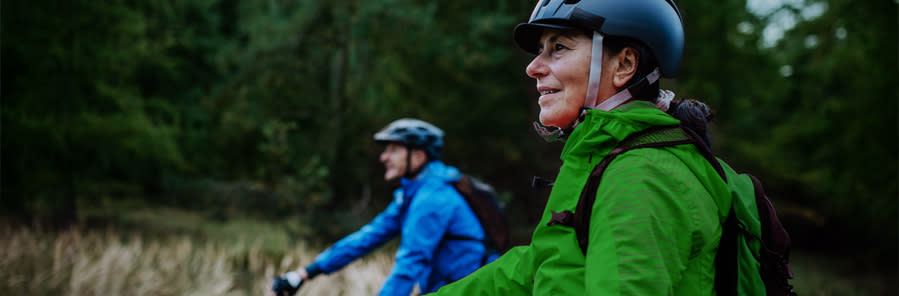 En man och en kvinna cyklar i skogen.