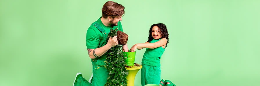 En vuxen och ett barn planterar en växt.