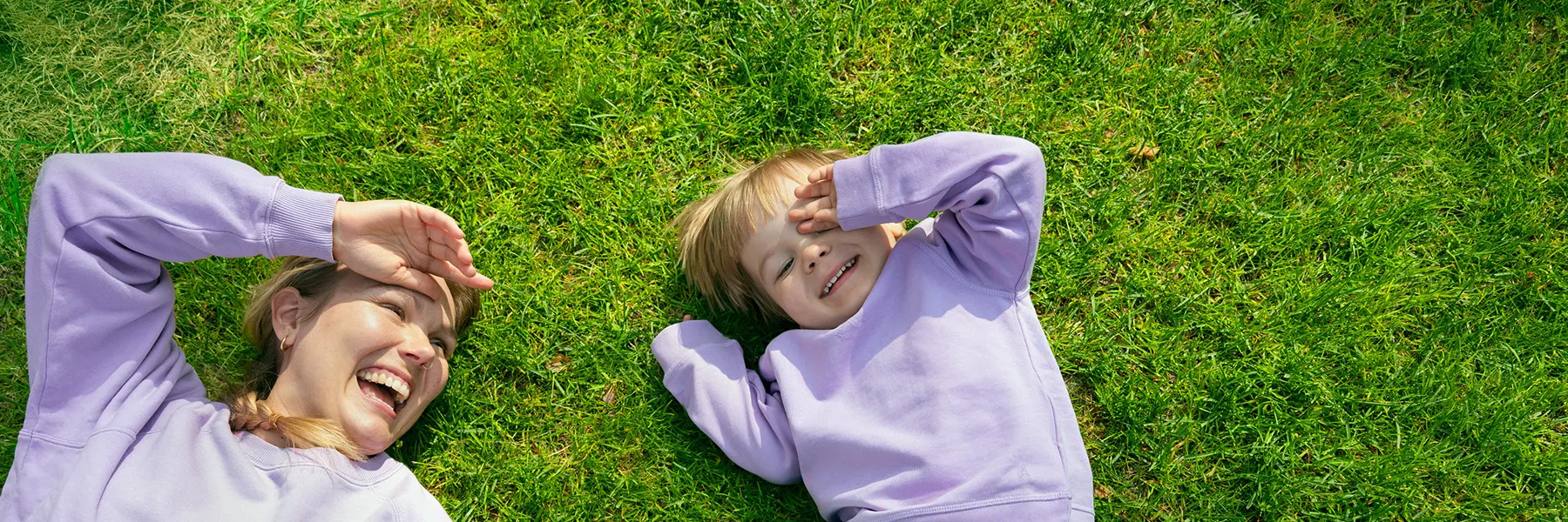 En kvinna och ett barn ligger i gräset.