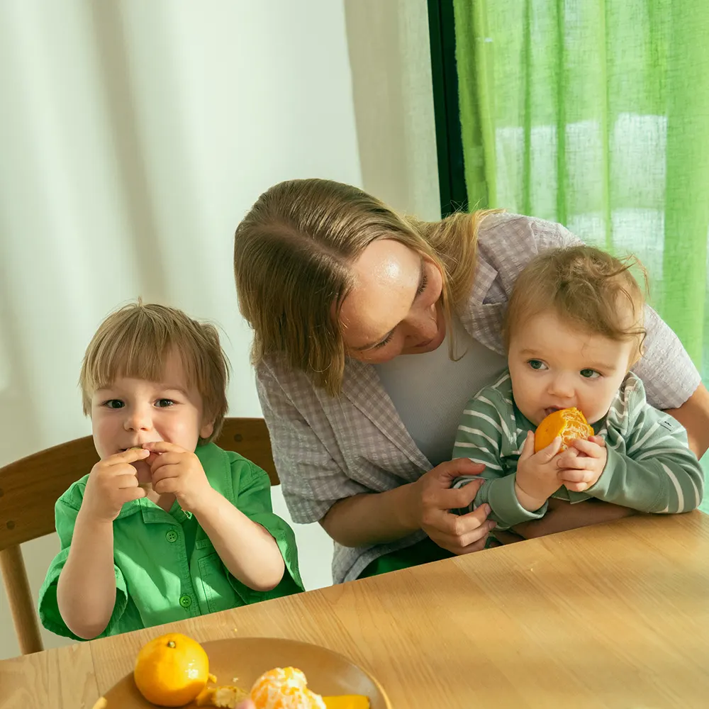En kvinna och hennes barn äter mandarin.