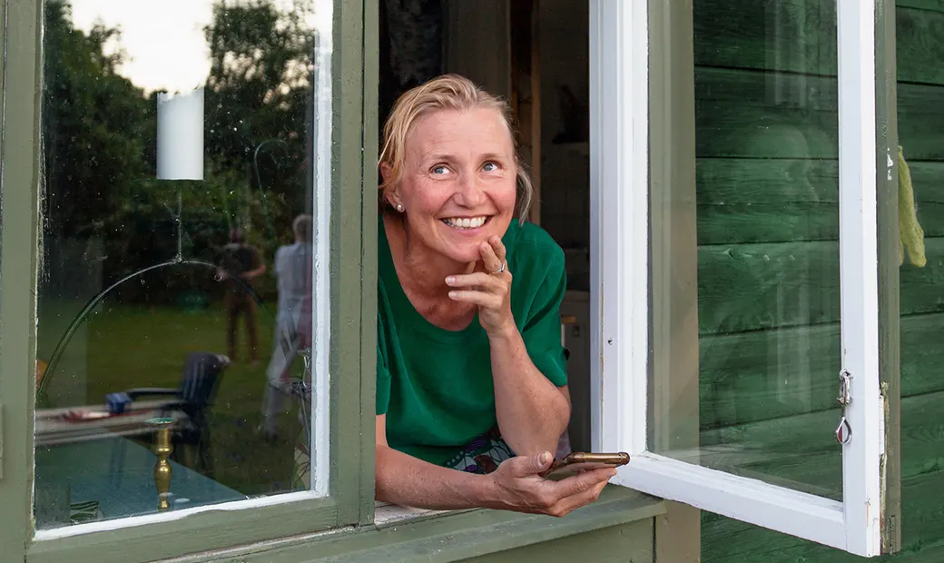 En kvinna vid stugans fönster.