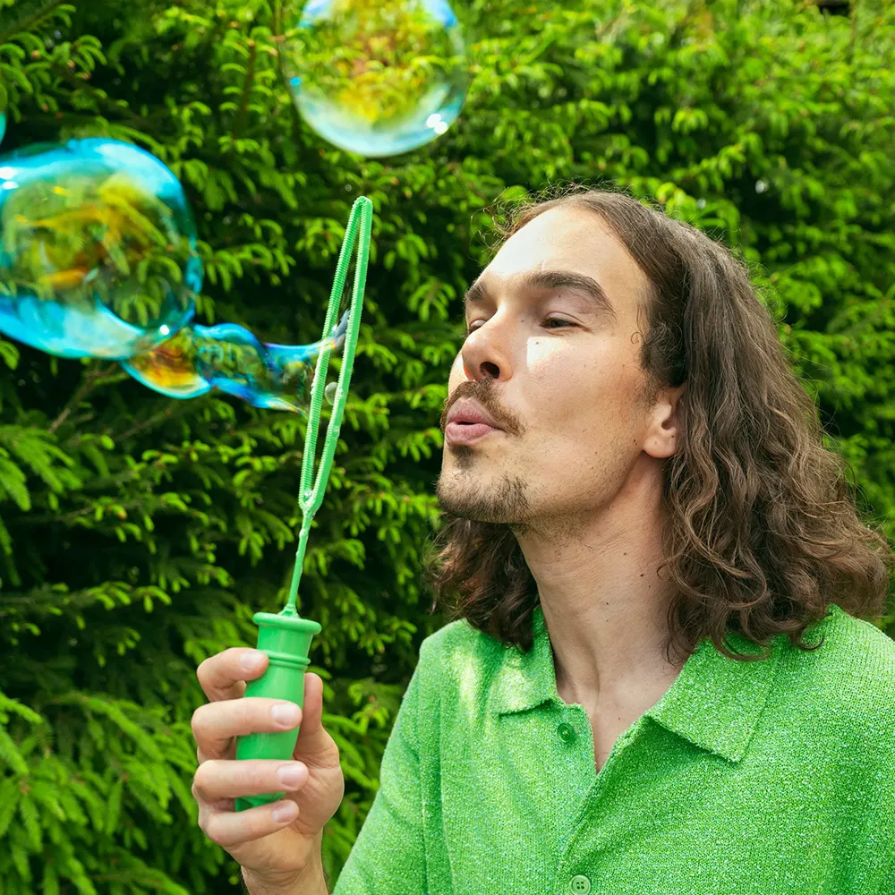 Mies puhaltaa saippuakuplia.