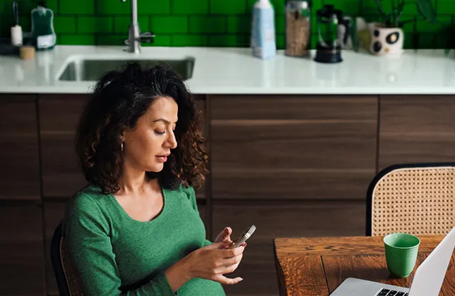 Kvinna sitter och bläddrar i sin telefon.