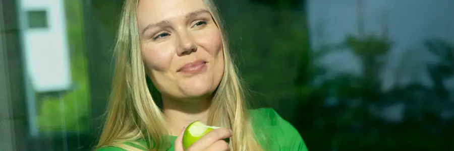 En kvinna äter ett äpple.