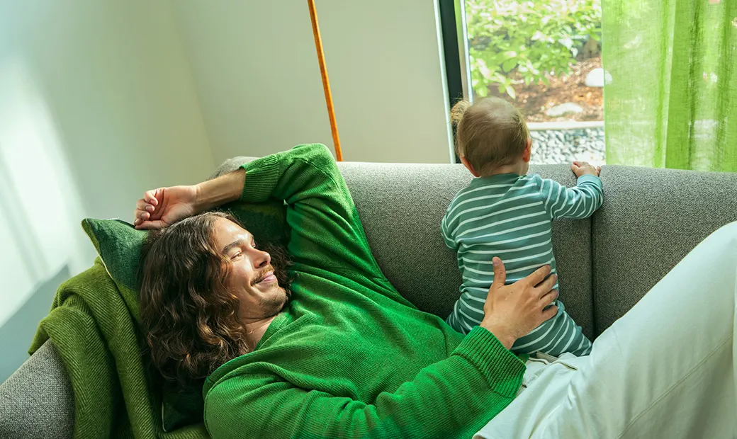 En man och en bebis på soffan.