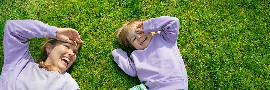 Nainen ja lapsi makaavat nurmikolla.