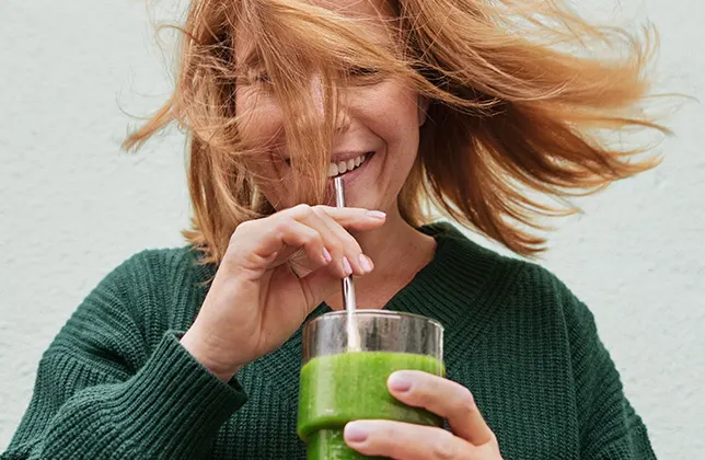 Kvinna dricker grön smoothie.