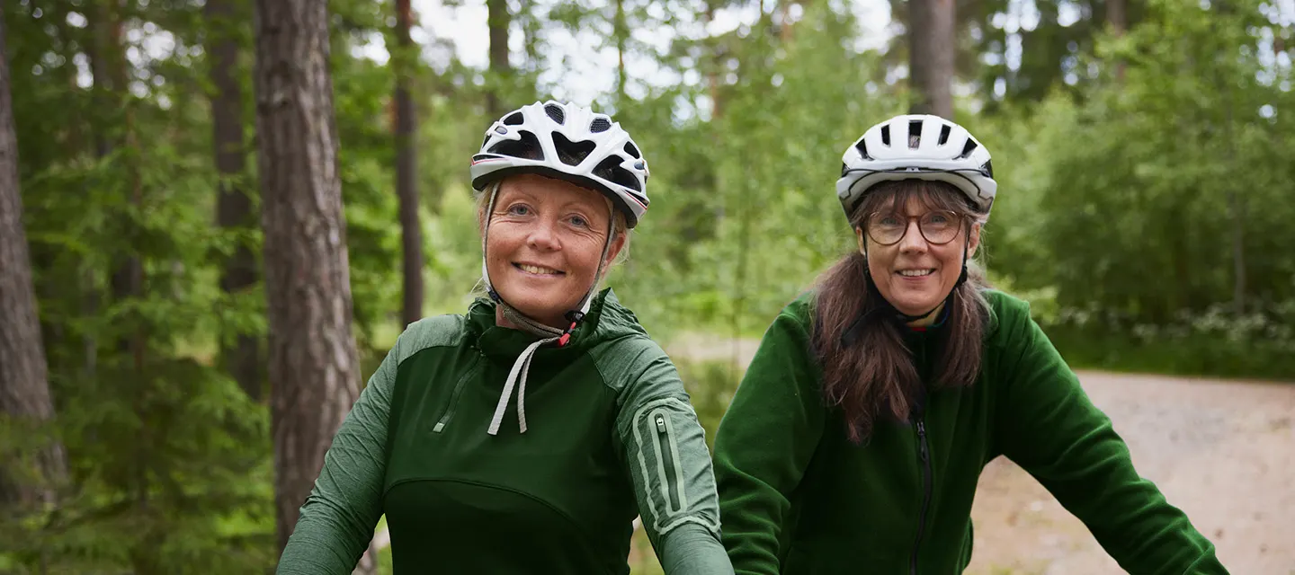 Kvinnorna cyklar i skogen. 