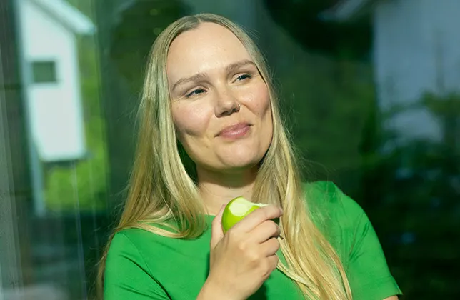 En kvinna äter ett äpple.
