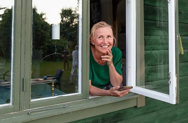 Kvinna ler vid fönstret.