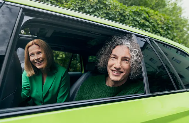 En kvinna och en man ler i bilen.