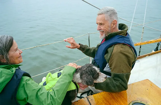 Kvinna, man och hund på en segelbåt.