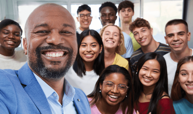 A high school teacher and students smiling at camera.