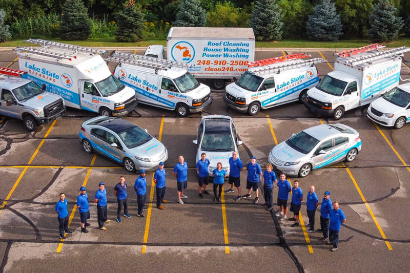 An aerial photo of a team and fleet of vehicles standing together in a parking lot.
