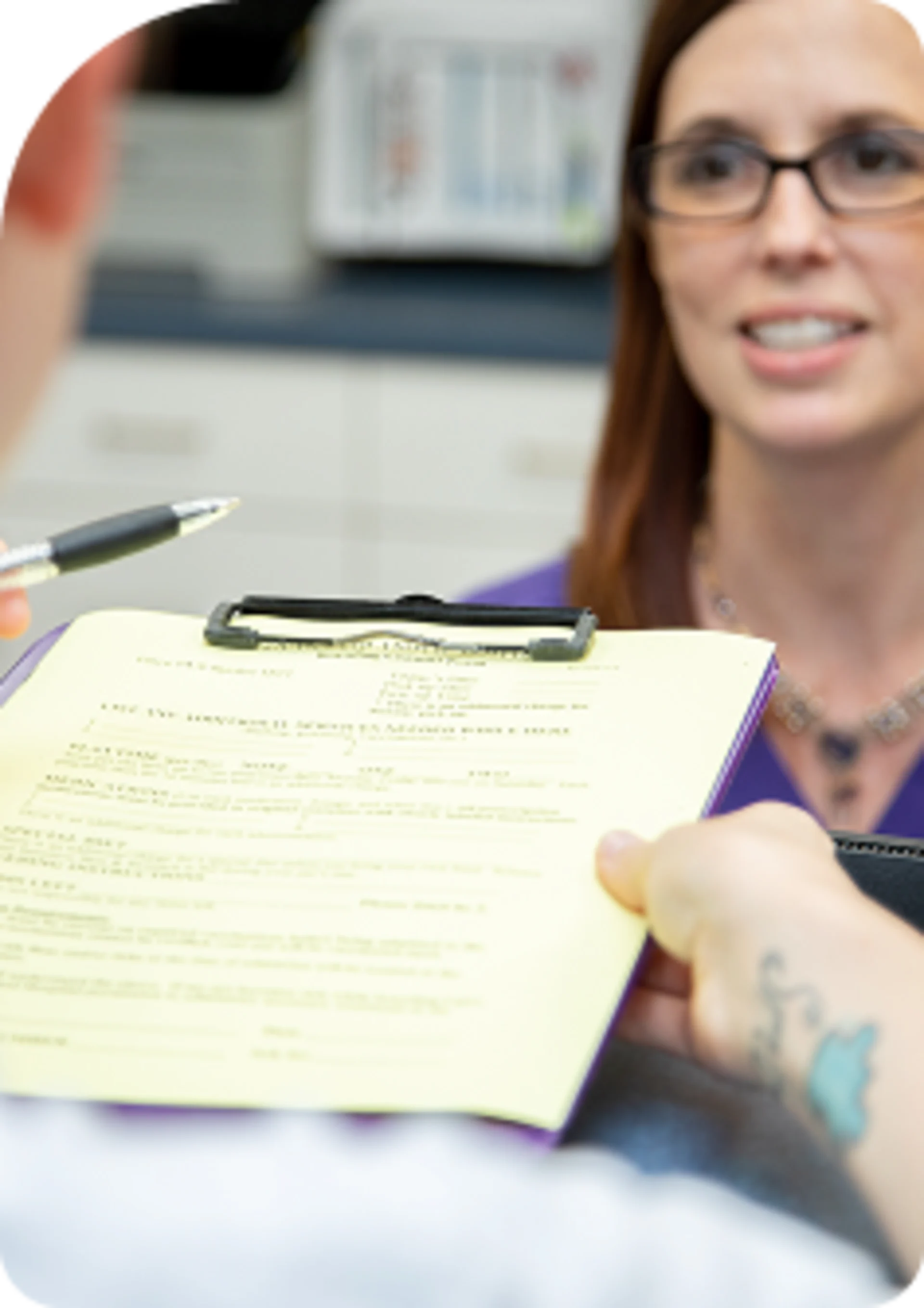 Patient or client filling out medical forms on a yellow clipboard during check-in at a clinic or veterinary office.