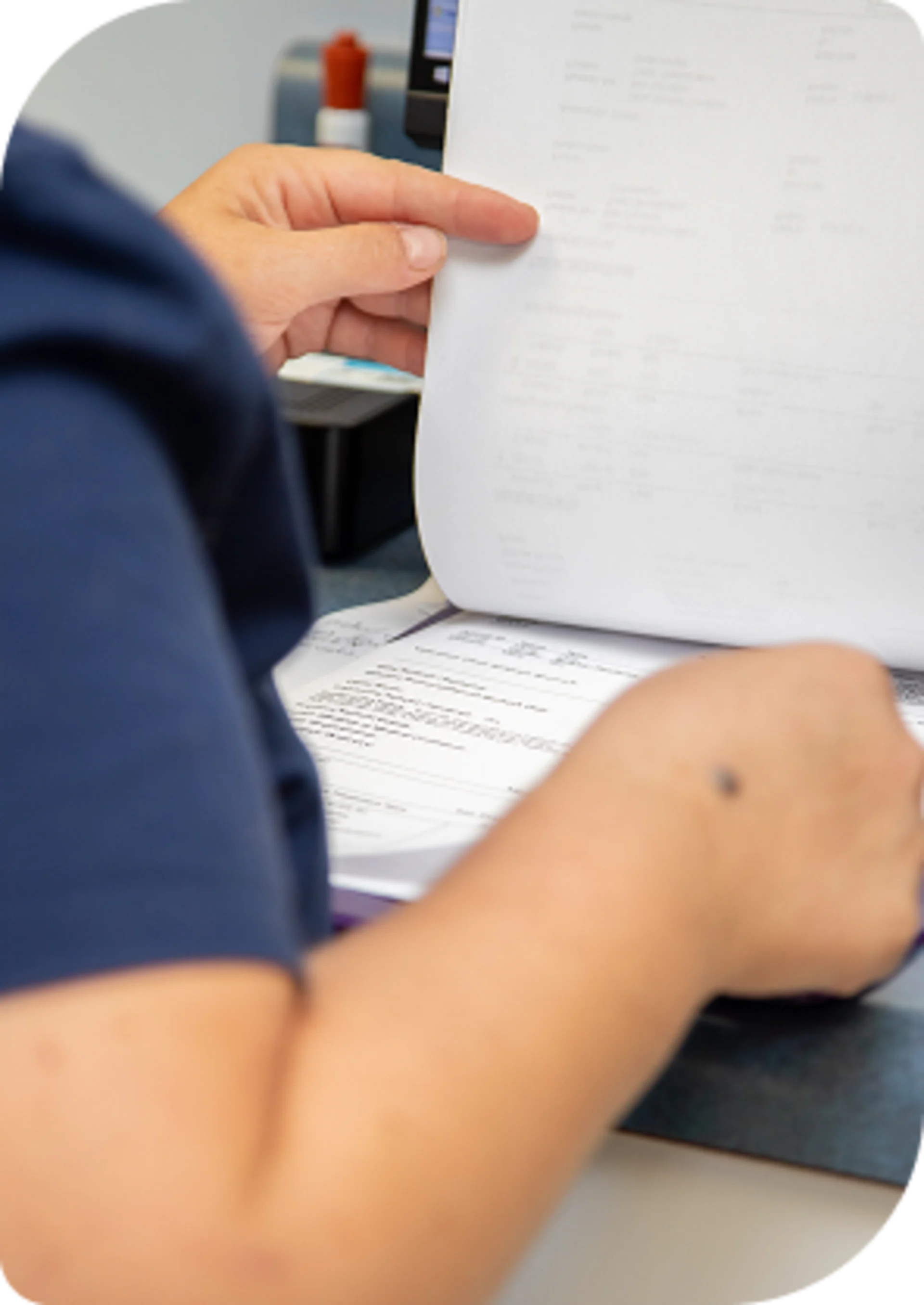 Hands of a vet technician or nurse sorting through a stack of paperwork and forms in a clinical office setting.