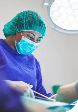 Medical surgeon in scrubs and mask working in an operating room.