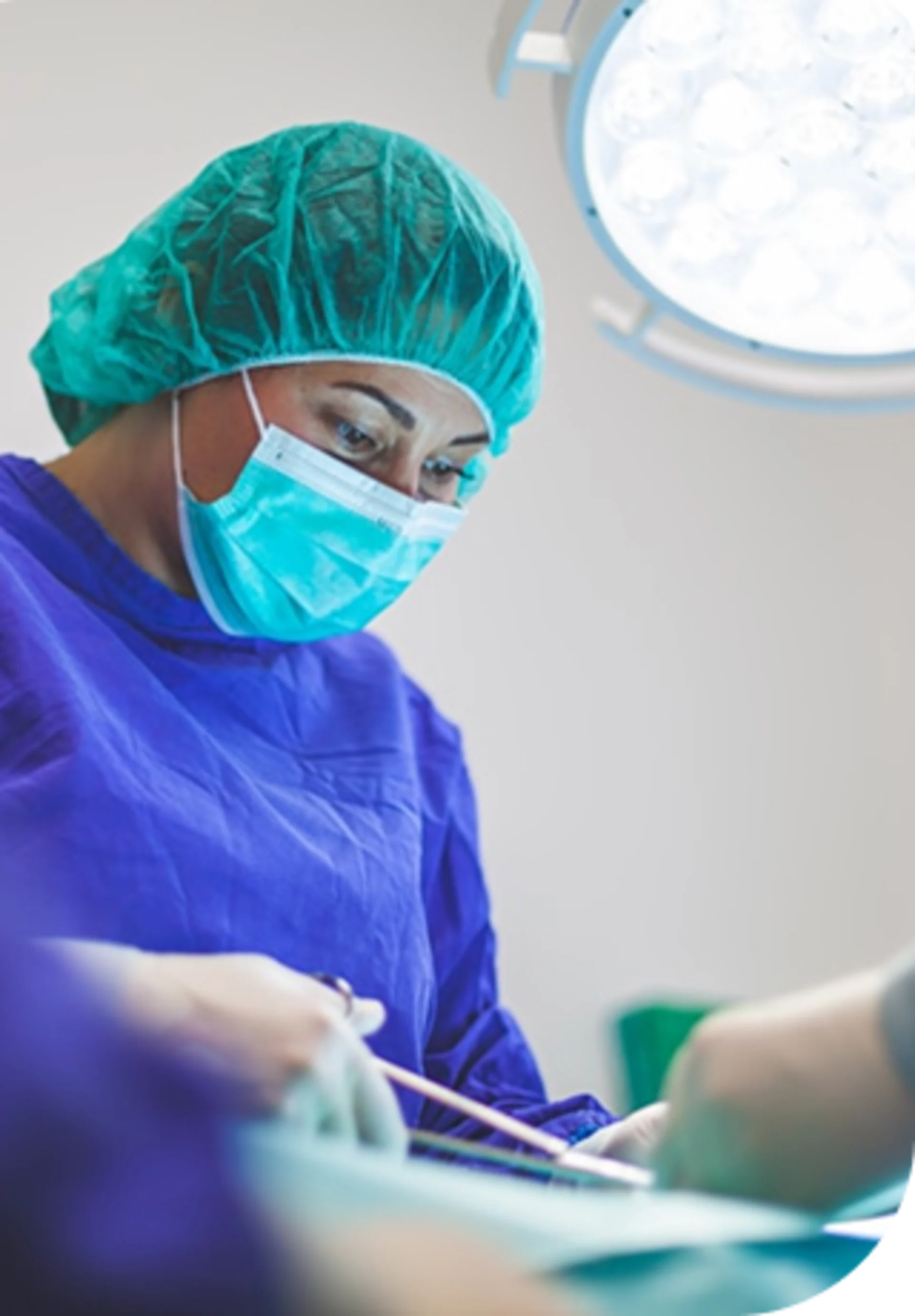 Medical surgeon in scrubs and mask working in an operating room.