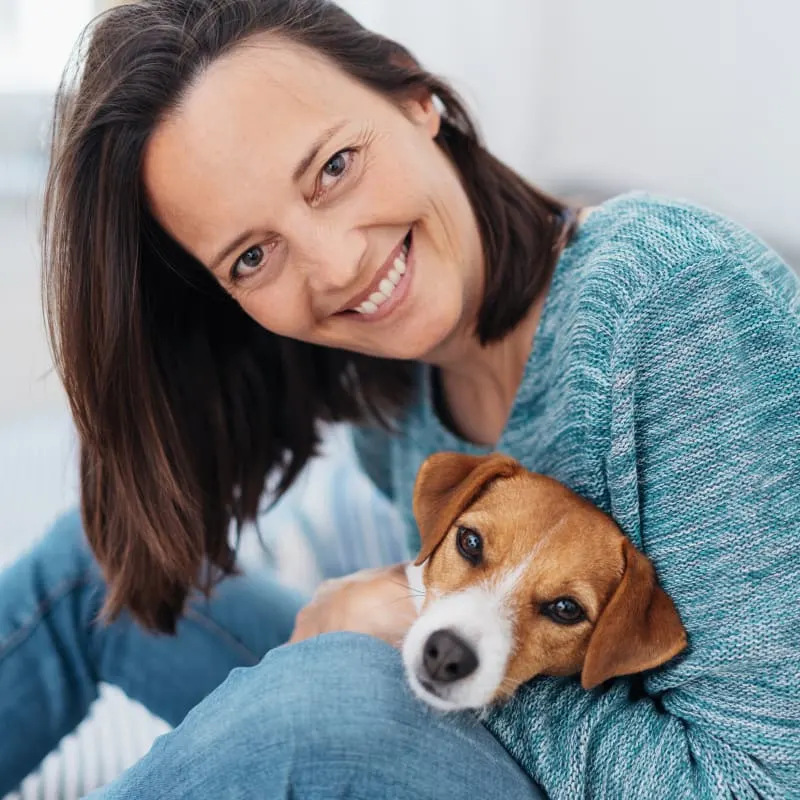 Happy lady sitting and holding dog between her legs Happy lady sitting and holding dog between her legs