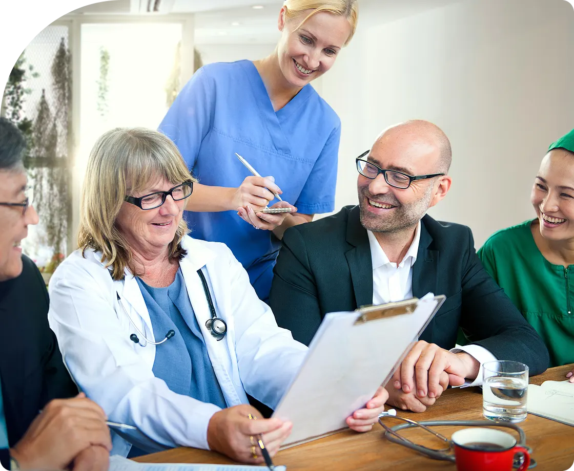 A group of veterinary professionals and clients sitting around a table, reviewing a medical document together in a collaborative meeting.