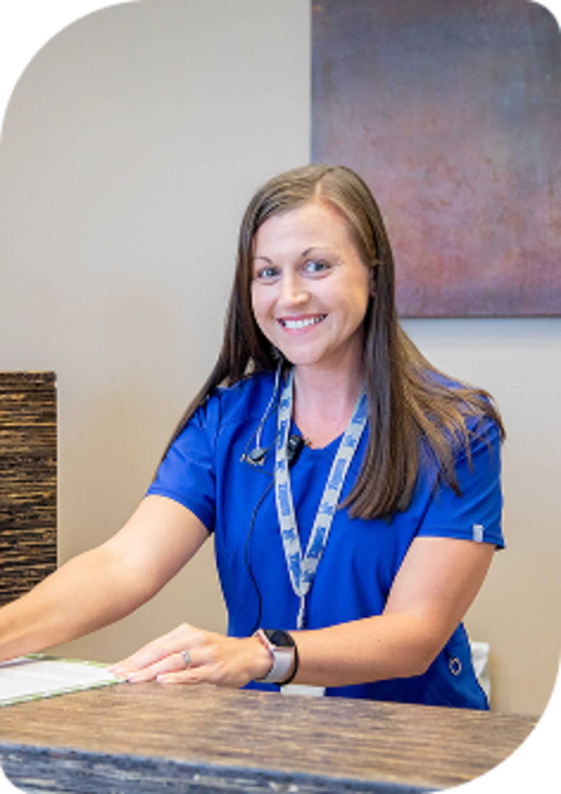 Smiling veterinary receptionist or clinic administrator in a bright blue uniform standing at the front desk.