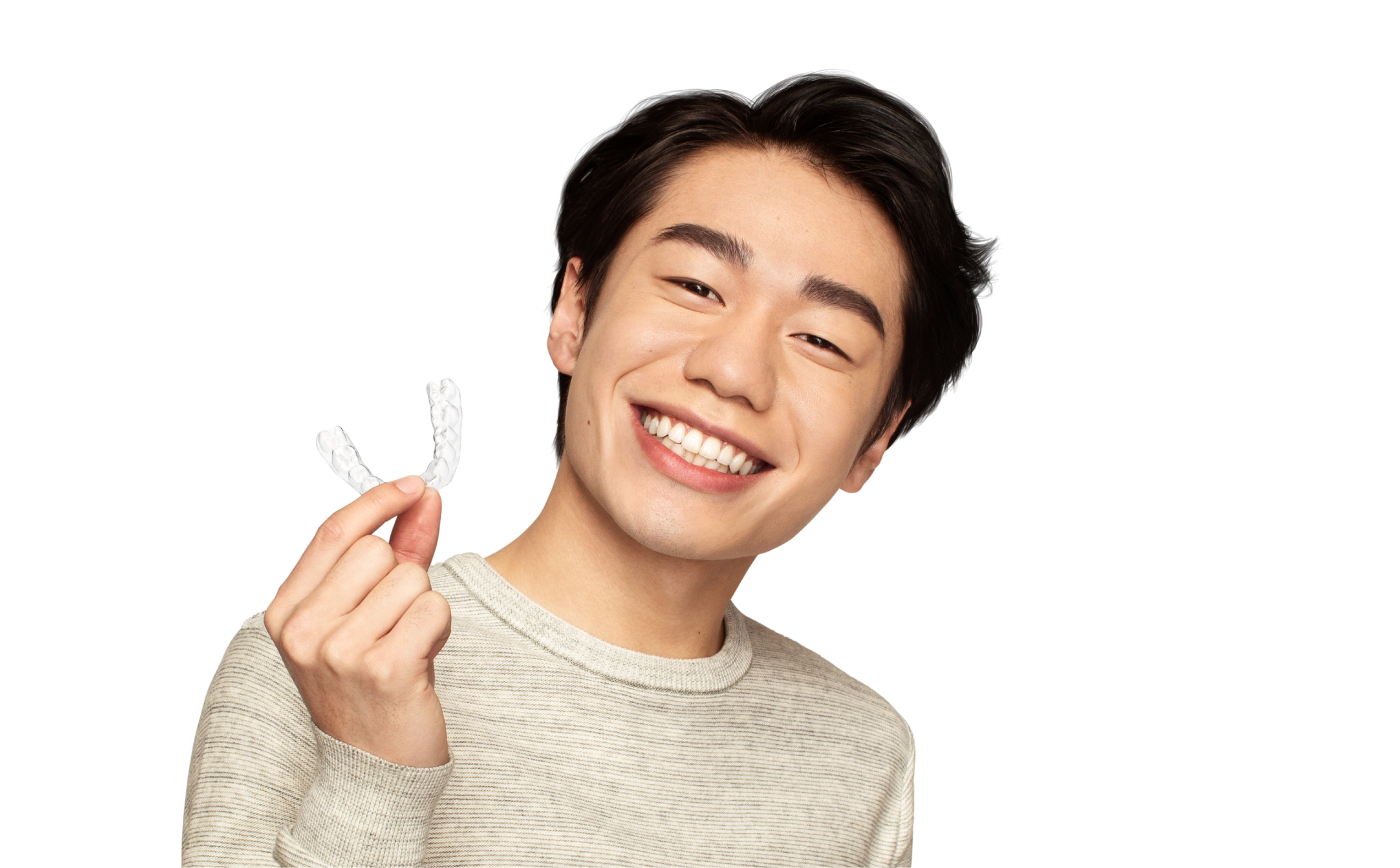 Asian man with black hair and a beige sweater smiling and holding SmileDirectClub Aligner