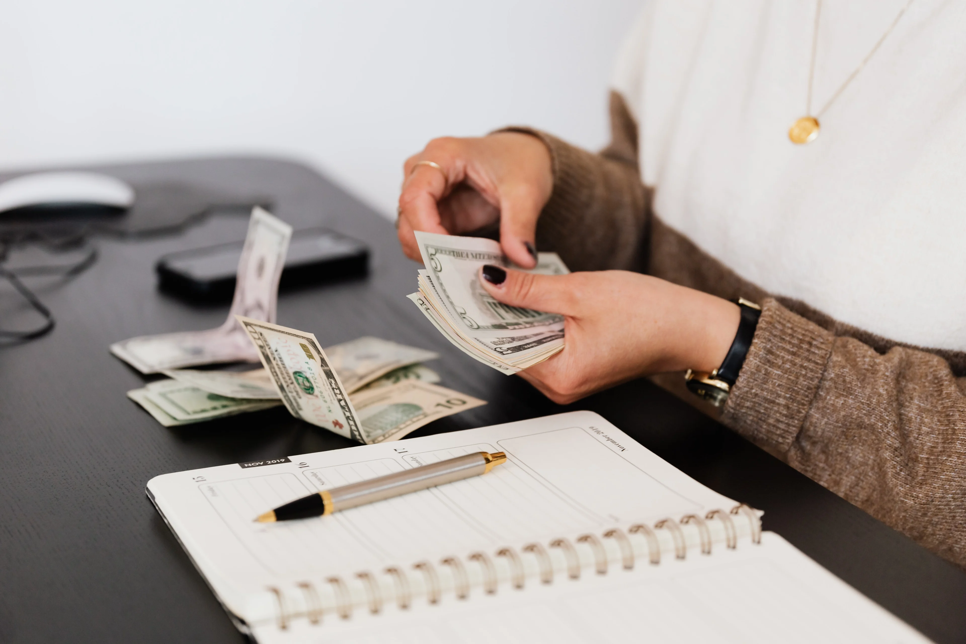 A woman counting cash accessed through an on-demand pay service