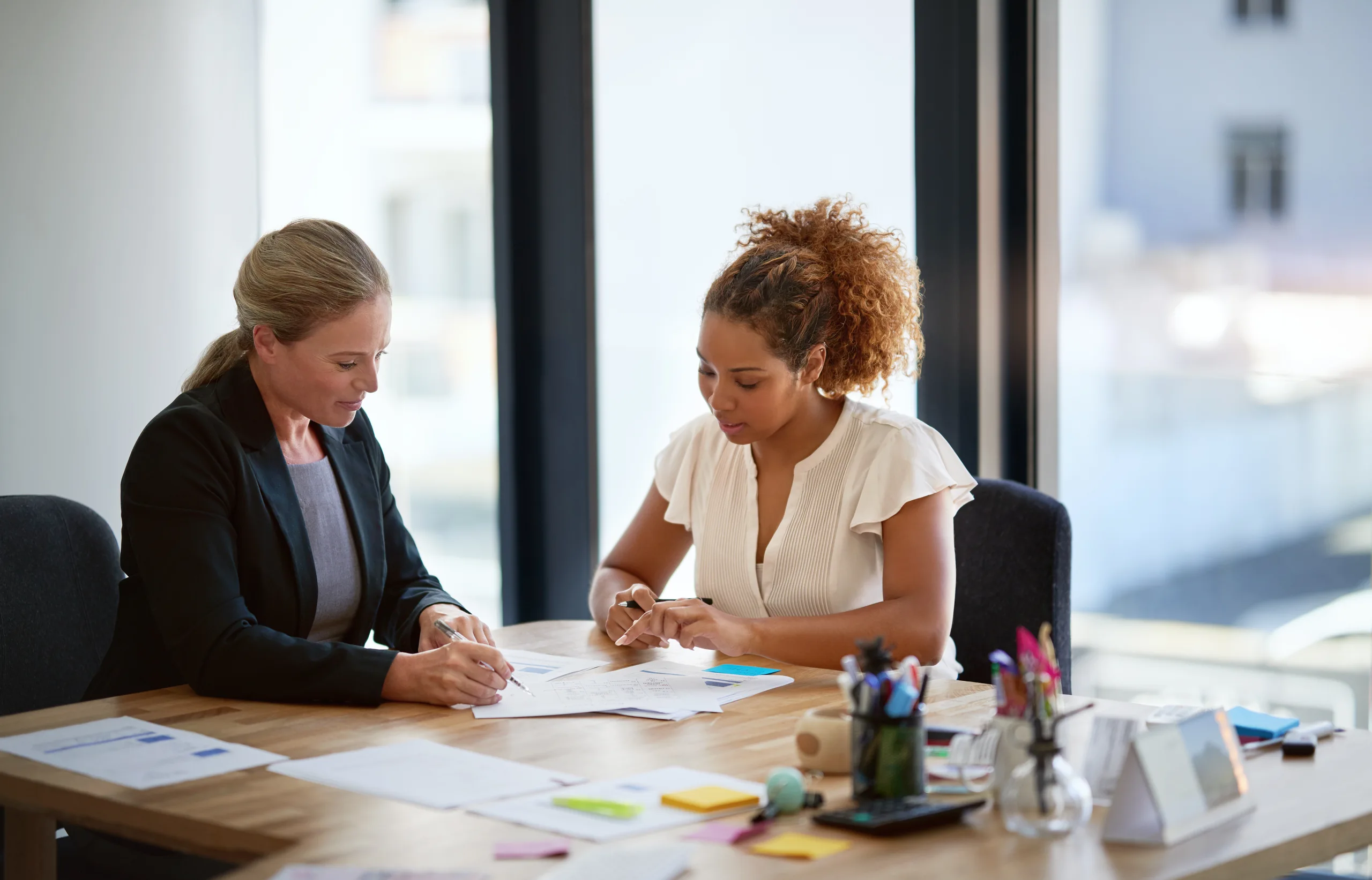 2 women are discussing the document in the office