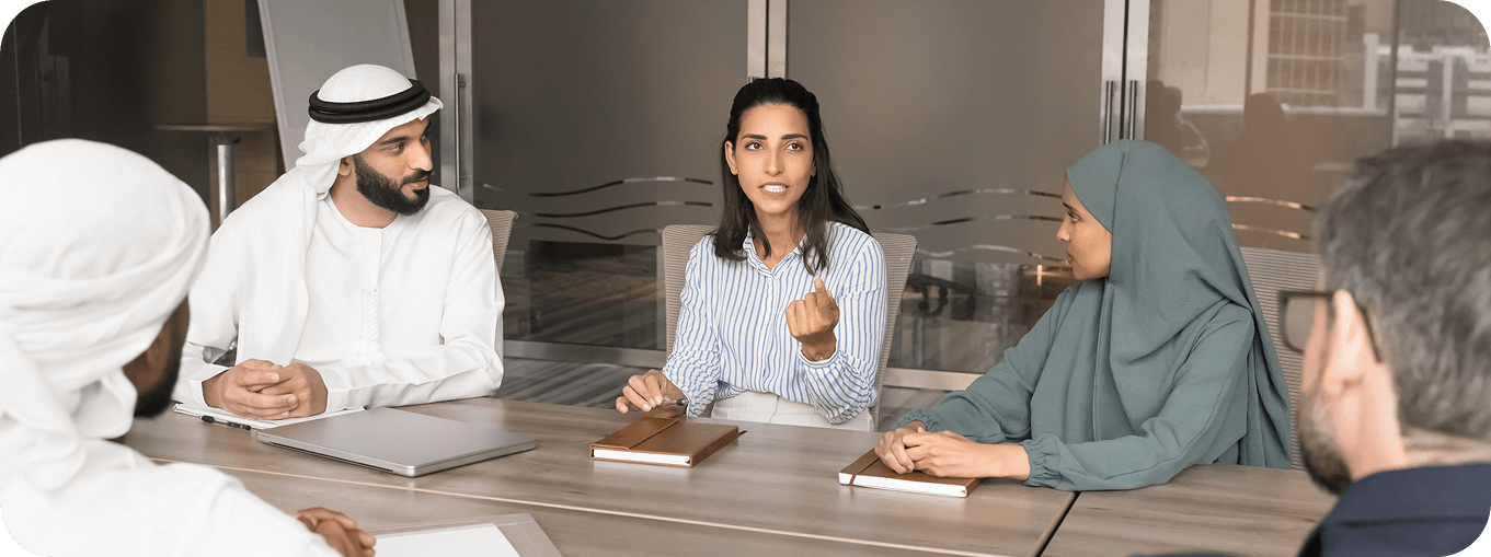 Diverse group of Qatari and international business professionals collaborating in a modern conference room.