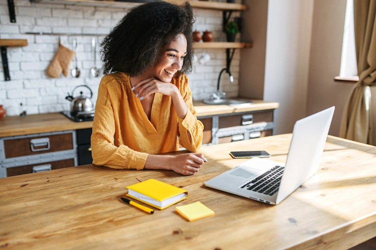 woman is on the working meeting using the laptop sitting in the kitchen