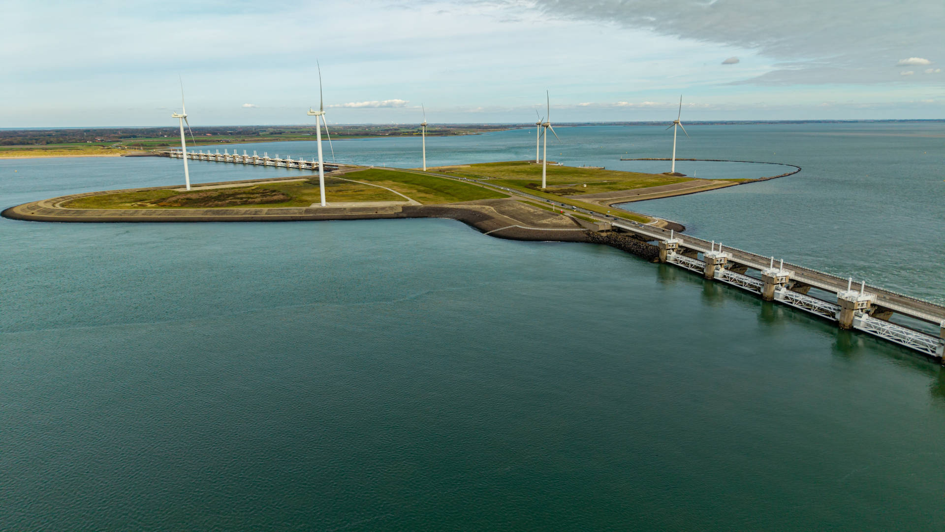 Landscape image of a sea coast with a two bridges and wind turbines