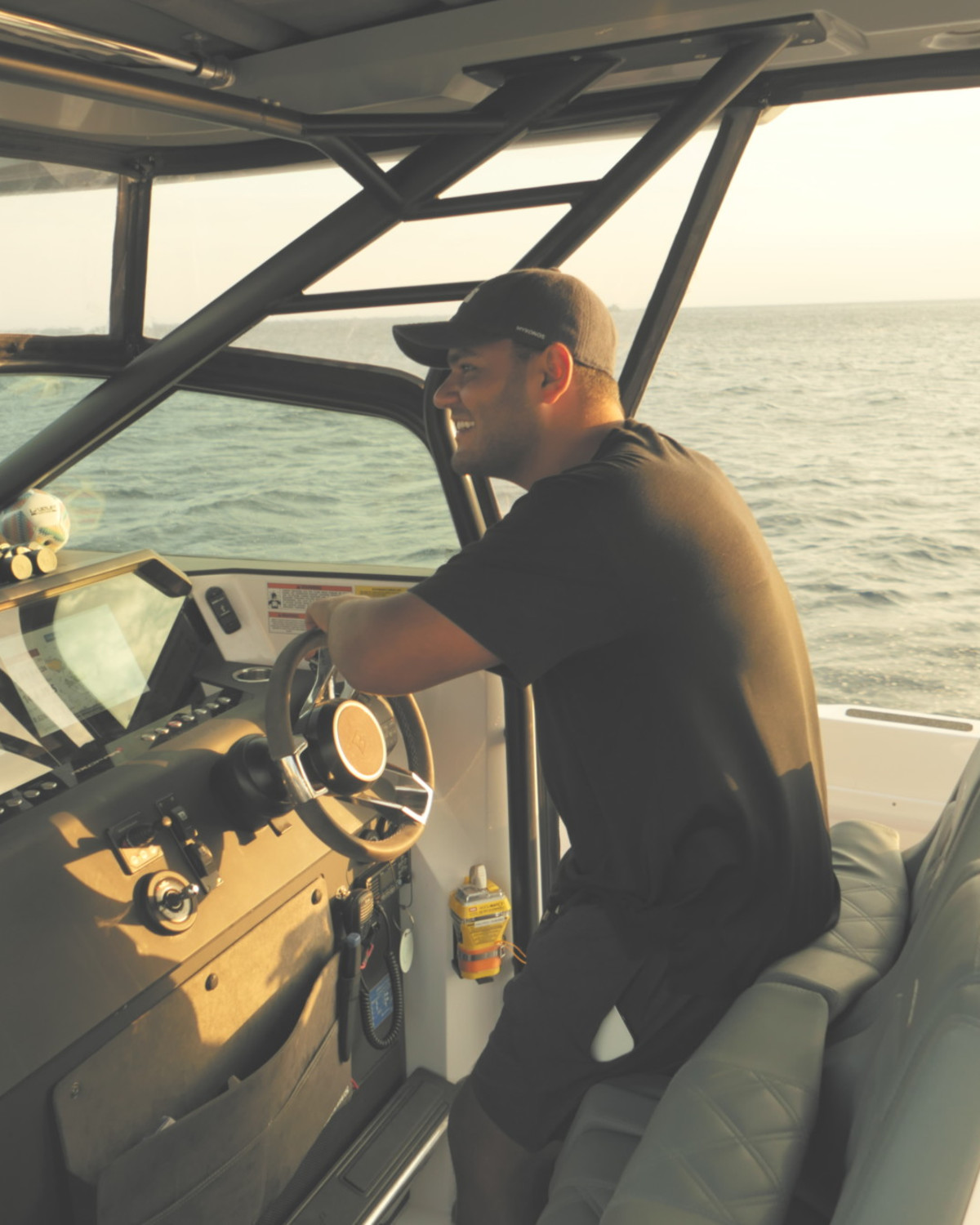 a man in a hat and tee shirt drives a small boat