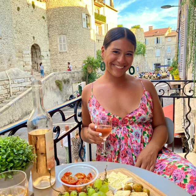 Travel Advisor Laura Rosas in a pink dress holding a glass of wine in front of a castle.
