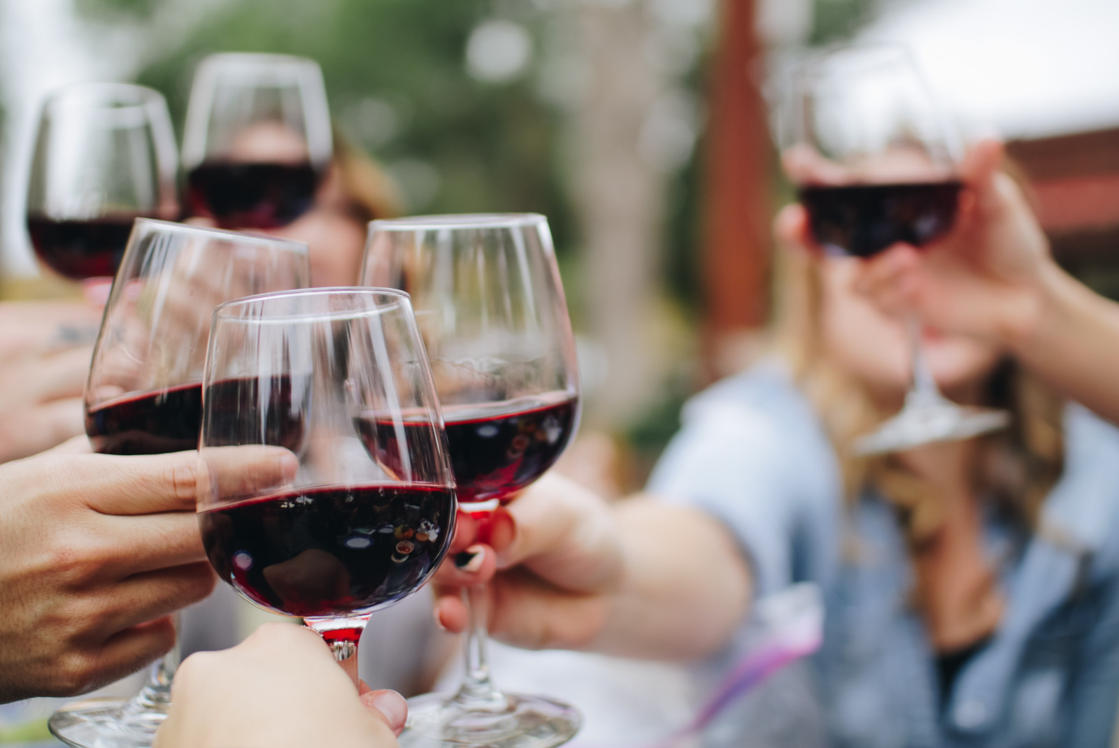 Six people cheers-ing with glasses filled with red wine