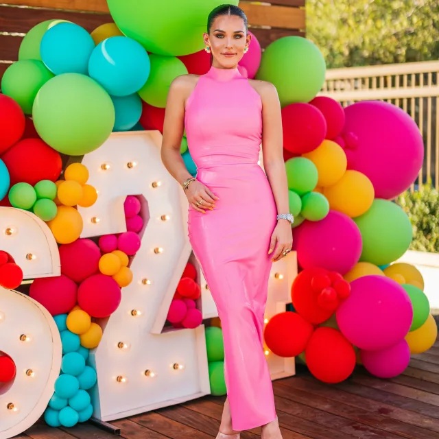 Tori posing in front of a balloon design while wearing a pink dress