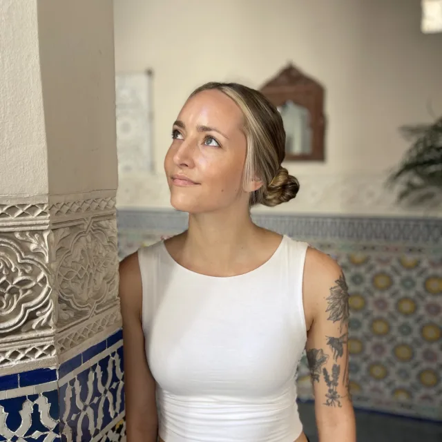 Travel Advisor Melissa Rytting wears a white tank top and leans against a blue and white tiled wall