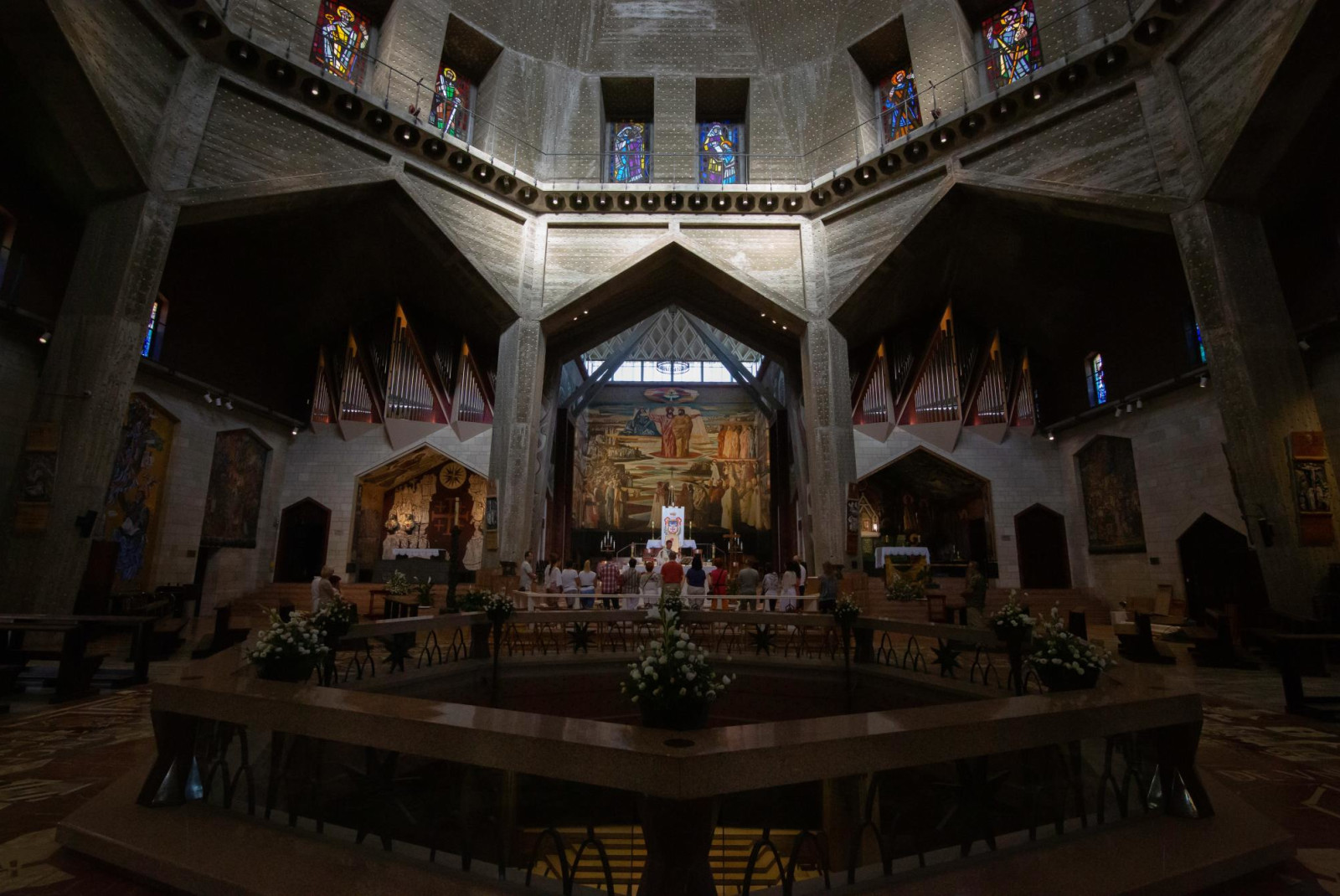 People worshipping inside grandiose and dim lit church in Nazareth. 