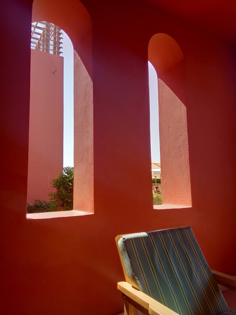 Coral wall with open windows and a wood chair