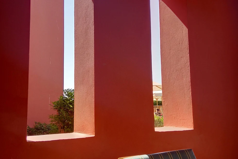 Coral wall with open windows and a wood chair