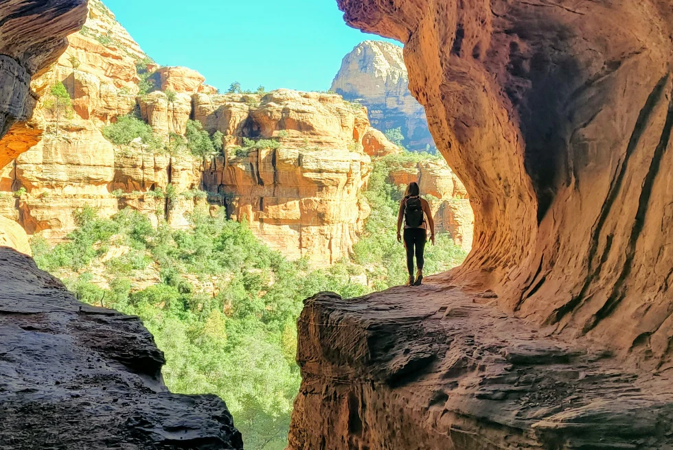 Person standing on red rock with blue skies during daytime