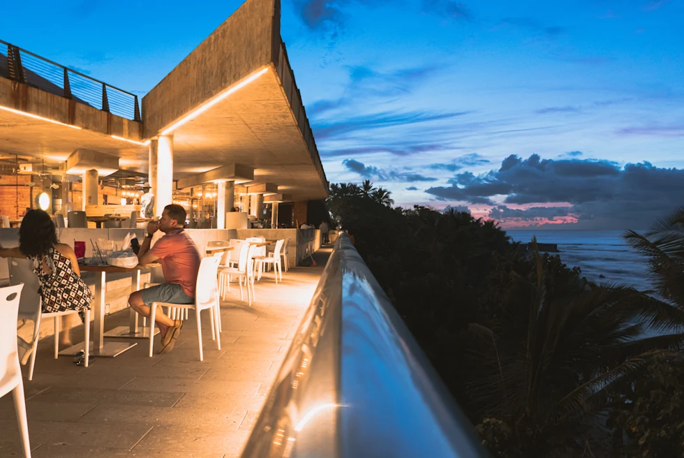 people sitting at restaurant next to ocean at nighttime
